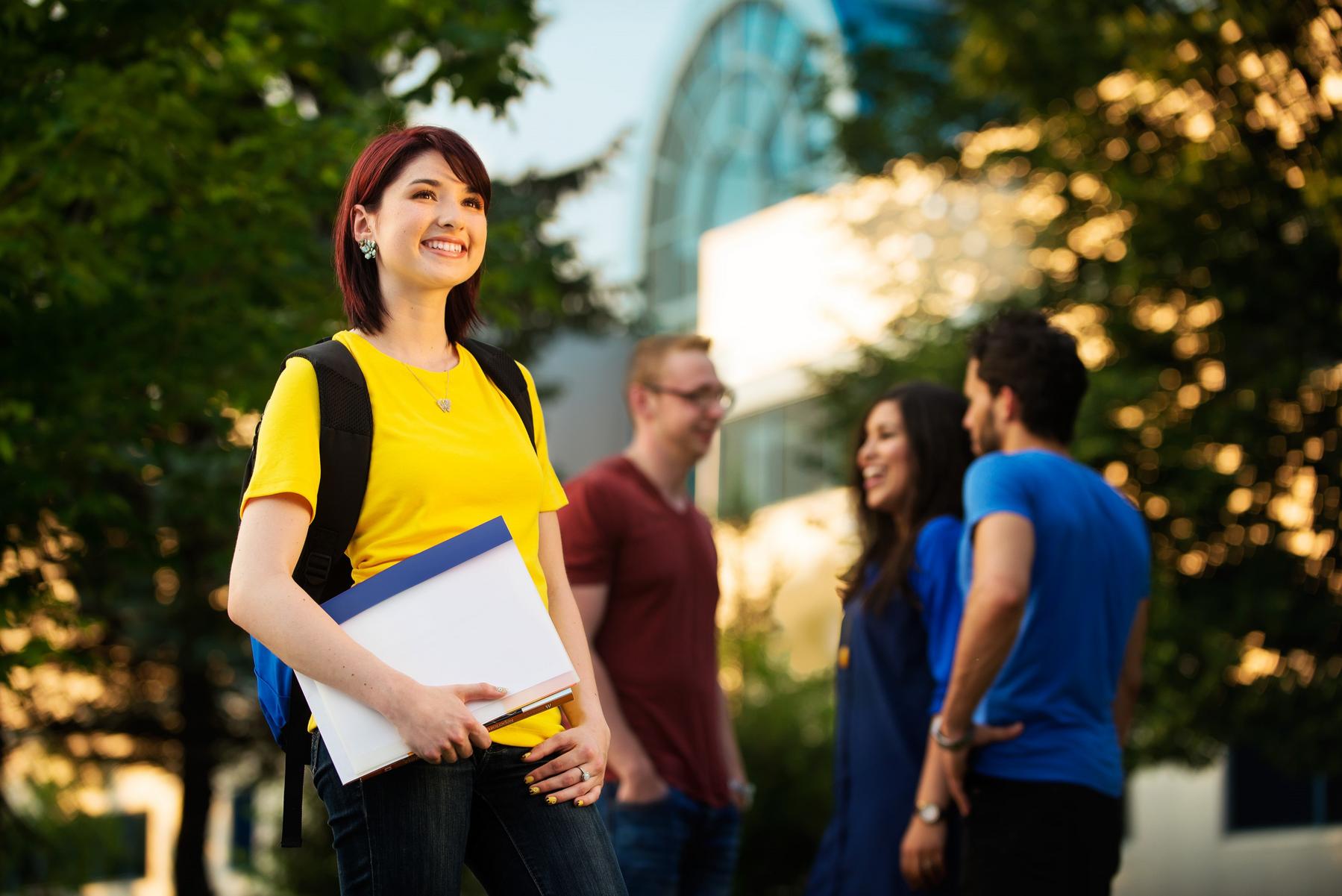 Young woman wearing a yellow T-shirt and a backpack, smiling