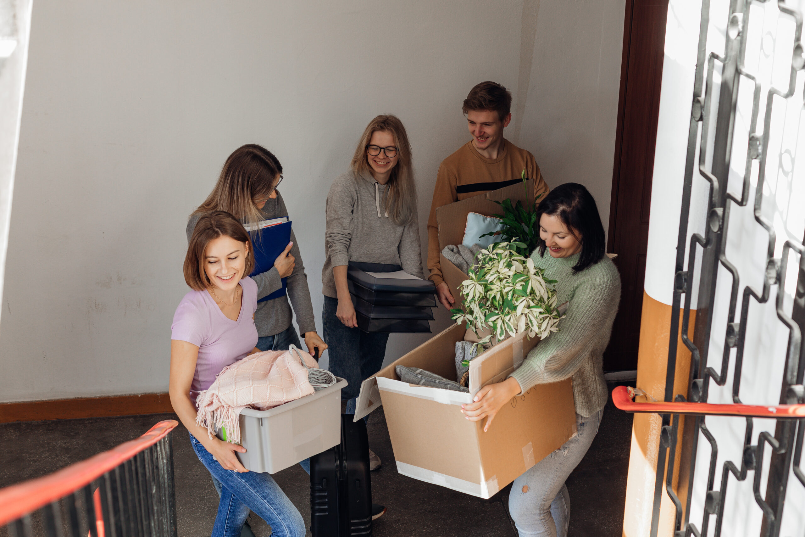 A group of people holding boxes in the hallway of the building as they move into a new home