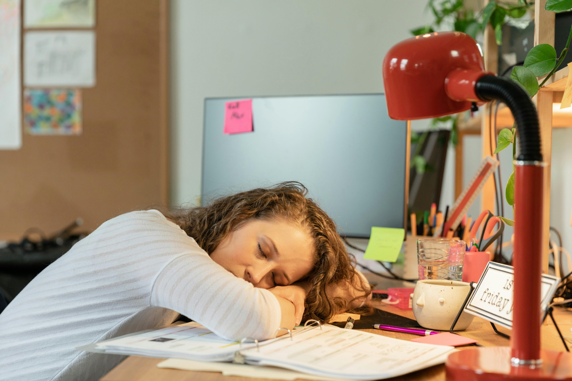Student sitting at a desk surrounded by books and papers  with unfinished assignments.